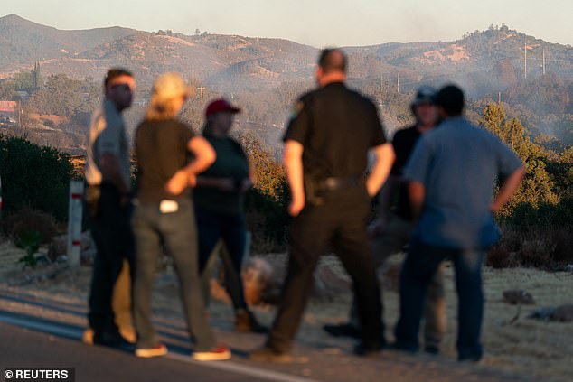 Law enforcement officers hold a conversation as the Boyles Fire burns in Clearlake, California