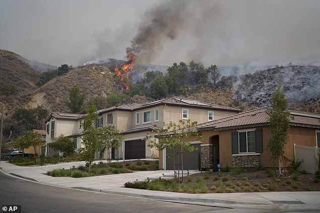 Flames from the Line Fire ignite over a residence on Saturday, Sept. 7, 2024, in Highland, Calif.