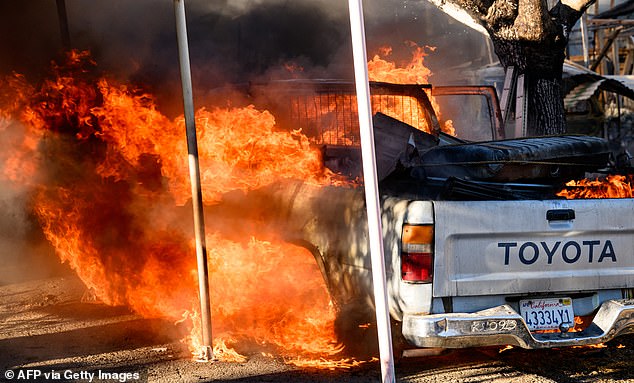 A truck burns in front of a residence as the Boyles Fire burns in Clearlake, California