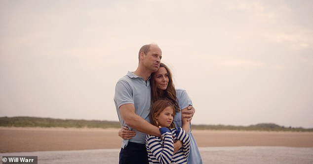 Princess Charlotte hugs her parents as they look out onto a beach in Norfolk