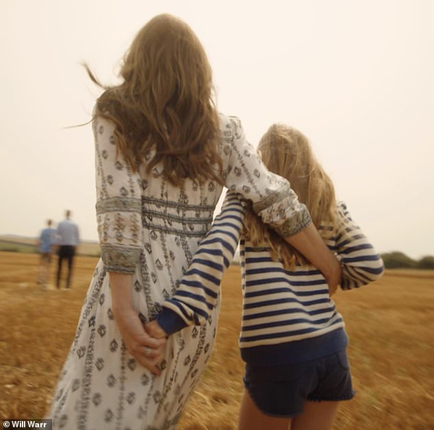 Catherine and Princess Charlotte hold arms as they walk through a field.