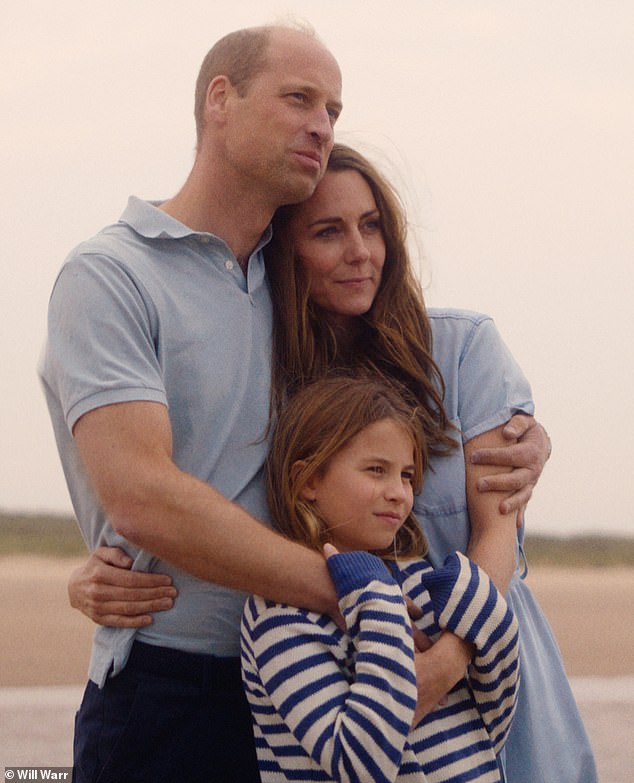 Princess Charlotte hugs her parents as they look out onto a beach in Norfolk