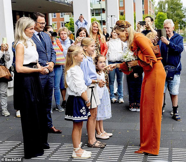 The royals chatted to the children after accepting a bouquet of white flowers at the event in the south of the Netherlands today.