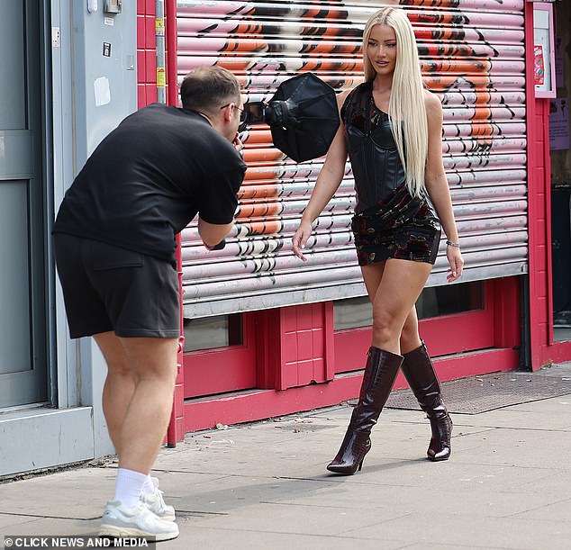 She paired this unique piece of clothing with a pair of maroon leather-look high-heeled boots that hit just below the knee.