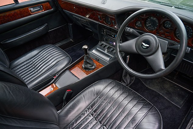 The Aston Martin has a black leather interior (pictured) and walnut trim, air conditioning and power windows.