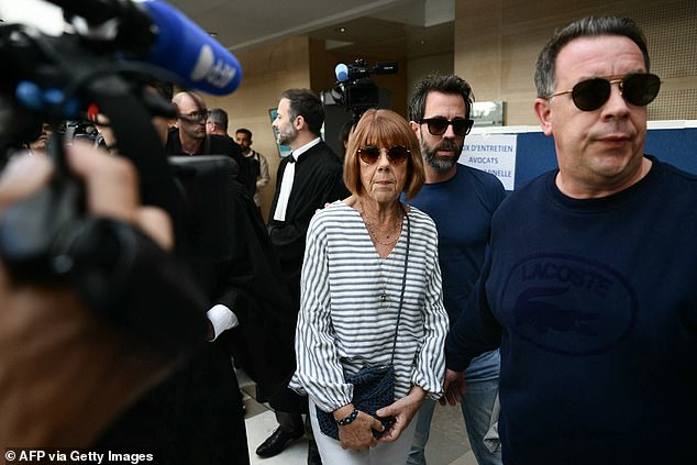 Gisele Pelicot faces reporters as she leaves the courtroom flanked by her sons Florian (back) and David (right) after attending a session of the trial of her ex-partner Dominique Pelicot accused of drugging her for nearly ten years and inviting strangers to rape her at his home in Mazan, a small town in southern France, at the courthouse in Avignon, Monday