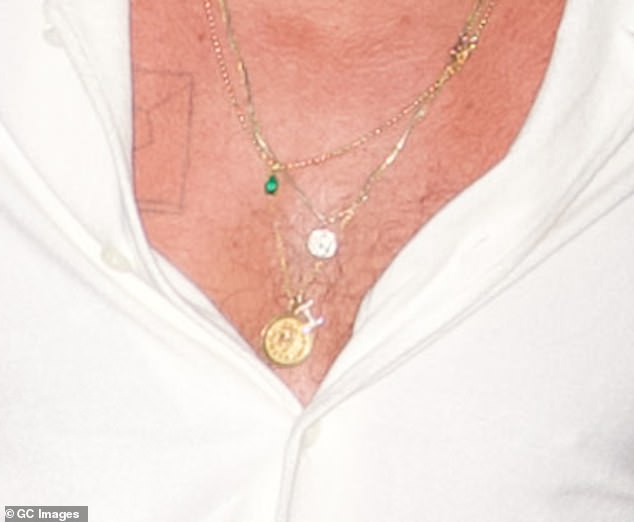 Brad's unbuttoned white shirt revealed a glimpse of his chest and a collection of necklaces, with a sparkling 'I' for Ines among them.