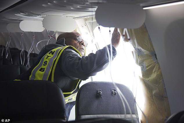 An investigator examines the frame of a section of Alaska Airlines Flight 1282