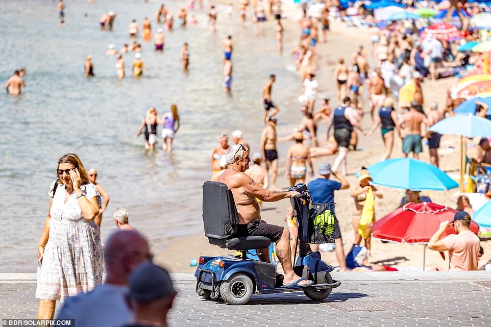 A man drives a mobility scooter along the beach in Benidorm