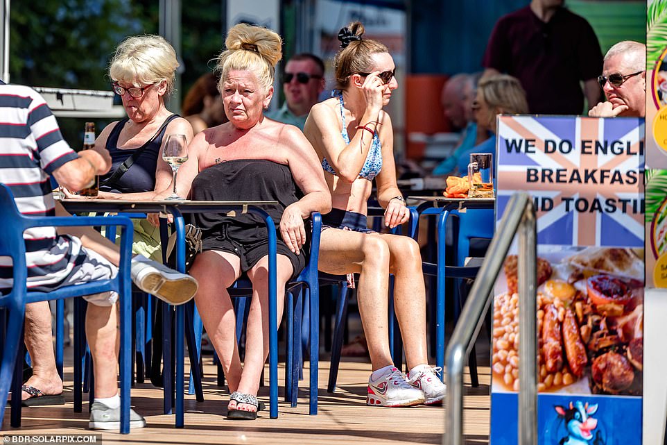 Tourists and expatriates sit at tables in a restaurant advertising English breakfasts.