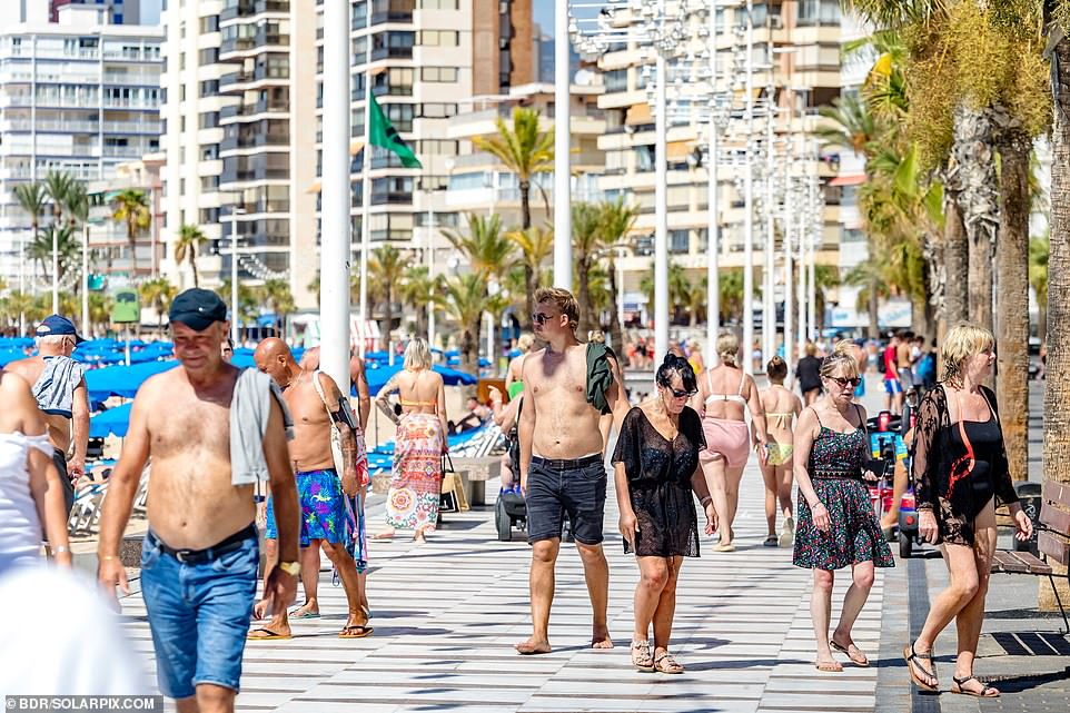 Tourists are seen walking along the beach in Benidorm on Wednesday