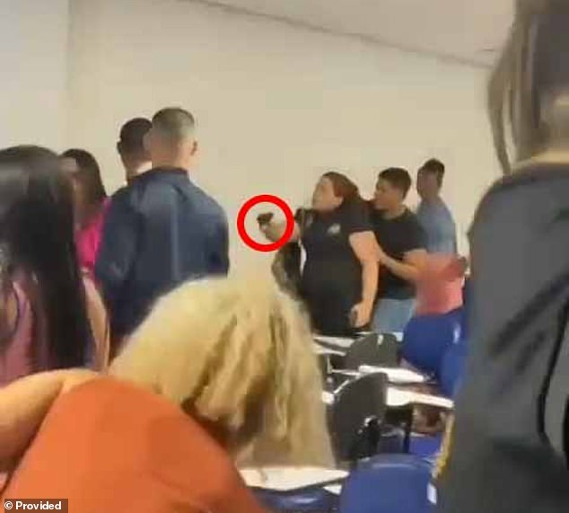 A female officer of the Civil Police of Alagoas, who attends Estácio Faculty, points her service weapon at a student during a fight after telling her to lower her voice during a lecture