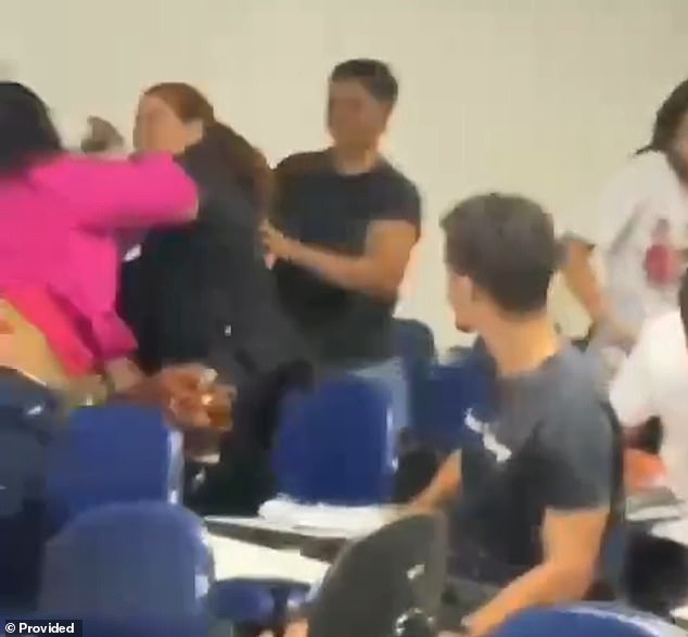 A student tries to separate two fighting students before one of them, who is also a police officer, points her unloaded gun at her classmate at Estácio College in Maceió, Brazil, last Friday. The Civil Police of Alagoas is investigating the police conduct