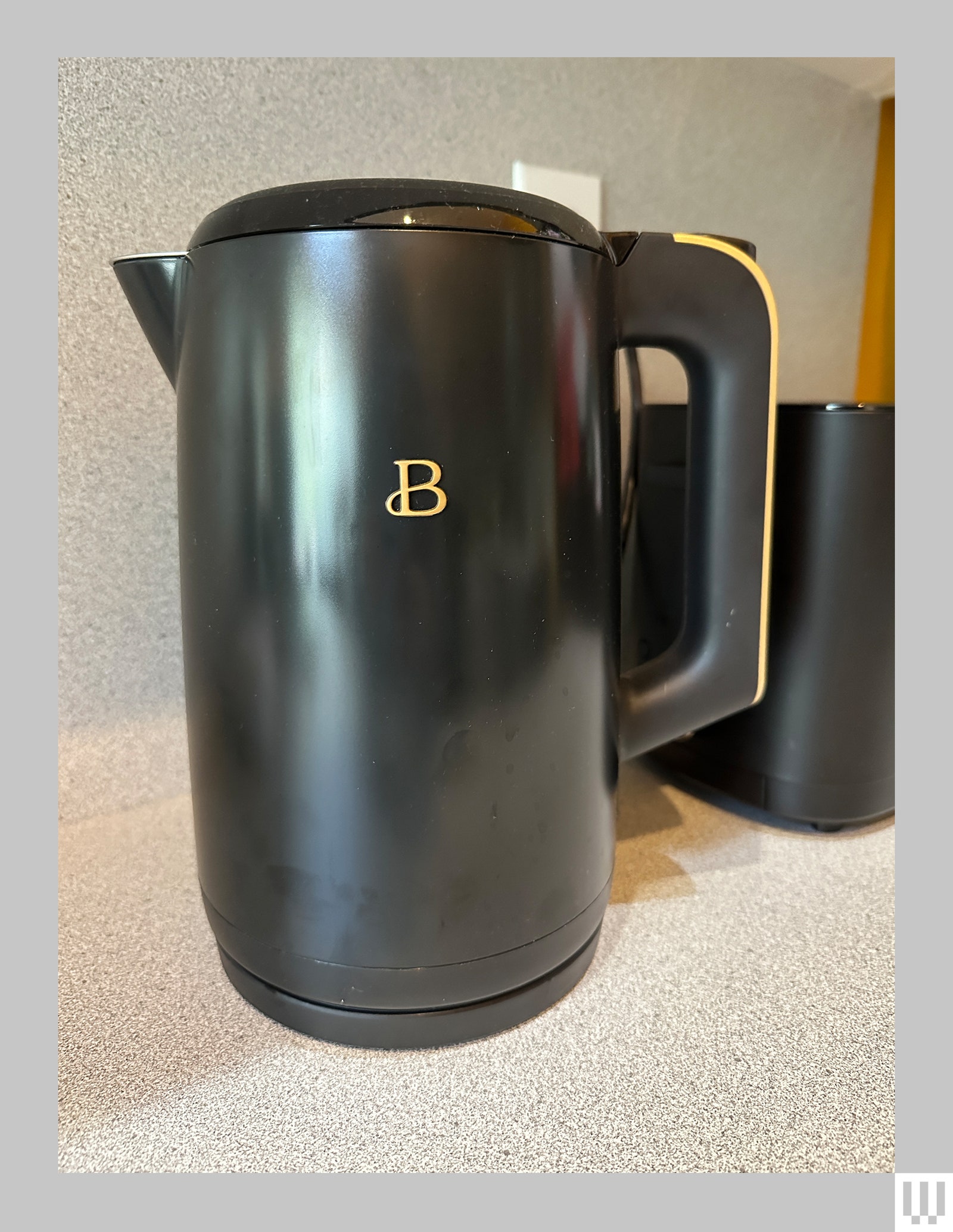 Black electric kettle with display off on a mottled kitchen counter