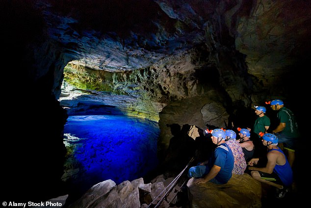 Above, tourists admire the 'Poco Encantado' (also known as 'the Enchanted Well'), a sunken underground pool and tourist destination in Chapada Diamantina National Park.