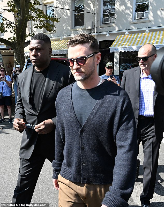 Timberlake is seen wearing a black cardigan with a black T-shirt underneath and khaki pants.