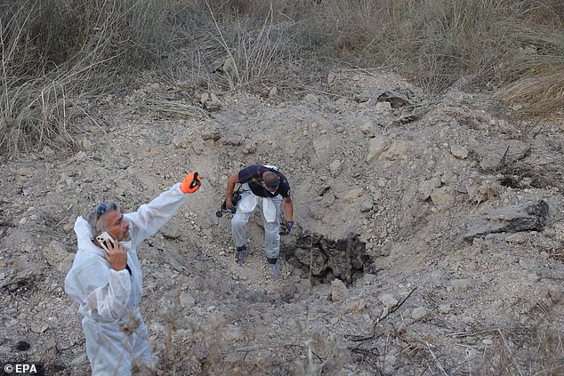 The Israeli police bomb disposal unit examines the site of a missile strike near Kfar Daniel in central Israel