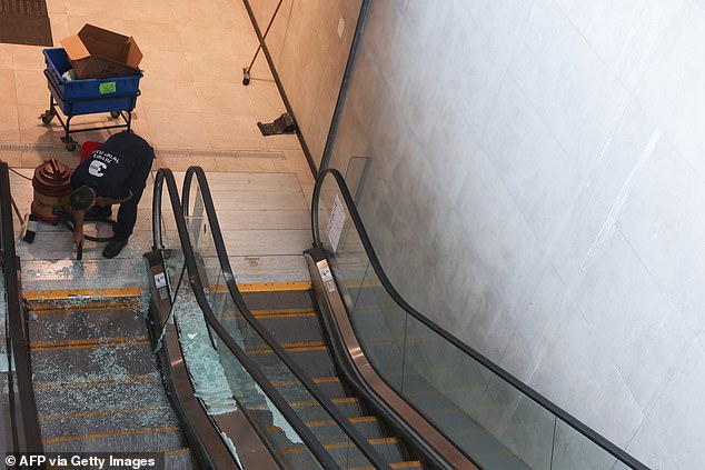 An employee sweeps glass shards from an escalator damaged by a missile hit from Yemen, inside a train station in the Israeli town of Modin.