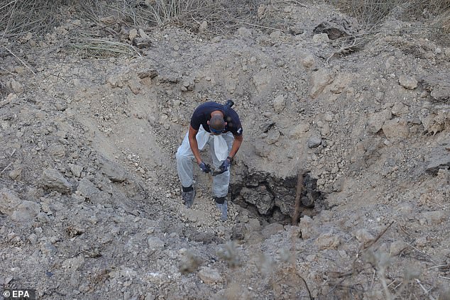 The Israel Police Bomb Disposal Unit examines the scene of a ground-to-ground missile impact near Kfar Daniel