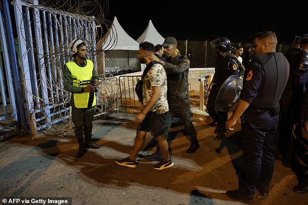 Members of the Moroccan Auxiliary Forces detain a man after they were deployed to prevent illegal crossings of the land border fence with the Spanish African enclave of Ceuta