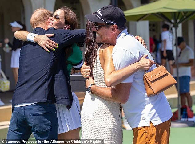 Harry hugs Kelly McKee Zajfen and Meghan hugs Julian at the tennis tournament on Saturday