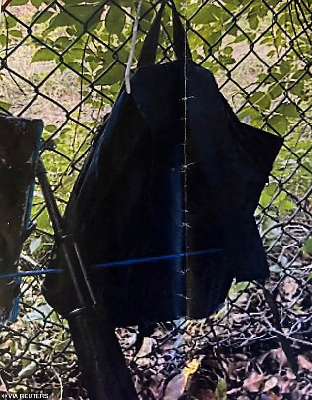 Law enforcement photos show fringes hanging from a fence over a rifle leaning against it.