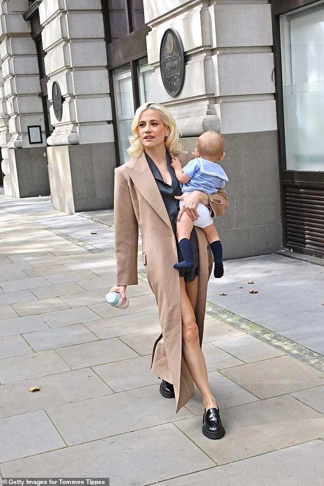 Sporting her signature peroxide blonde locks, the new mother wore a floor-length camel-coloured coat over a shorts suit.