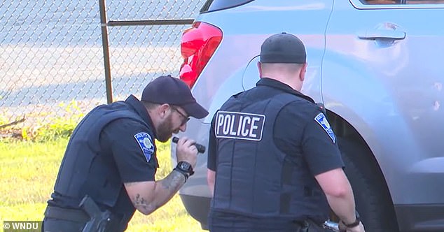 At the time, White's other daughter, aged six, said her mother was driving faster than usual, resulting in her sister getting her foot caught in the rear wheel of the car. (pictured: police look at the rear wheel)