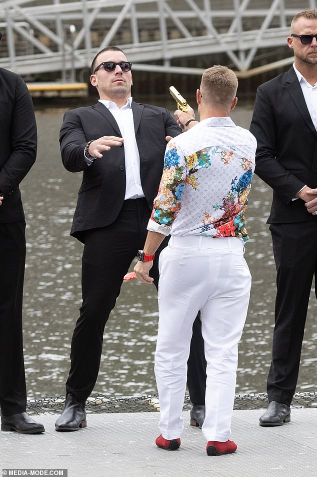 David wore a button-down shirt and white pants with a colorful floral print that contrasted sharply with his red shoes.