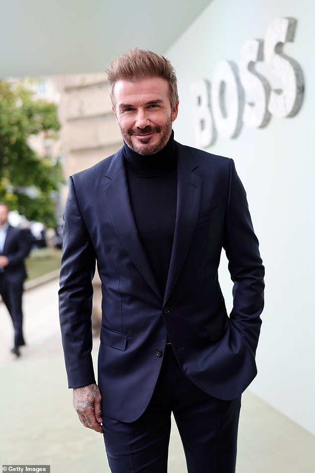 The 49-year-old former footballer cut a dapper figure in a navy suit and matching turtleneck.