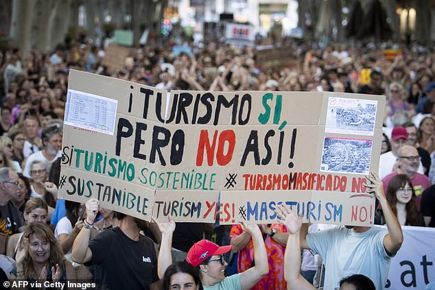 Protesters hold a sign reading 'tourism yes, but not like this' during a march in Palma