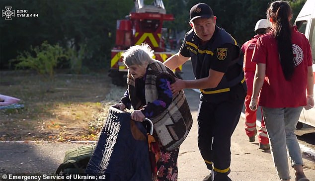 An elderly woman is helped out of a nursing home to safety by a rescuer.