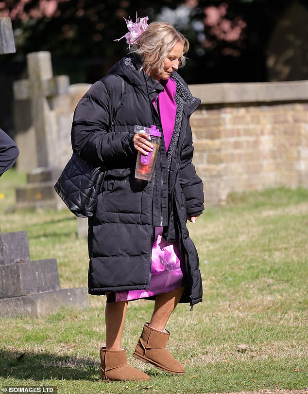 The blonde beauty wore her hair up in an elegant bun with a pink feather hair clip and wrapped in a long black padded coat.