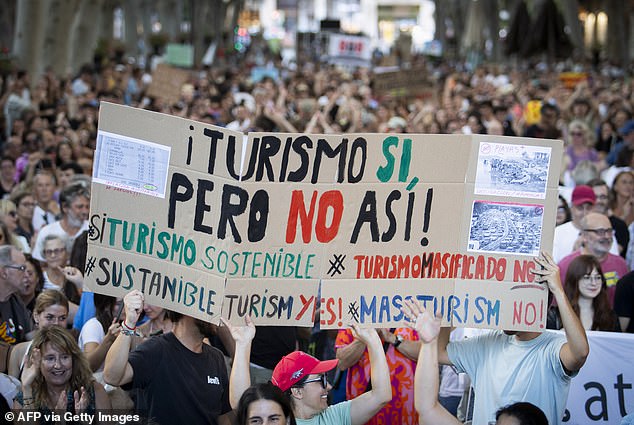 Protesters hold a sign reading 'tourism yes, but not like this' during the march in Palma