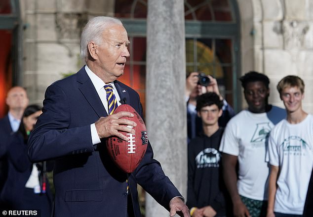 Biden mimes throwing a pass while visiting with members of the football team at Archmere Academy, his former school and site of the upcoming Quad summit, in Claymont, Delaware.