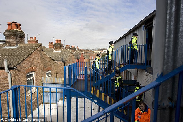 Once through the gates, fans climb metal stairs that ascend over residential gardens.