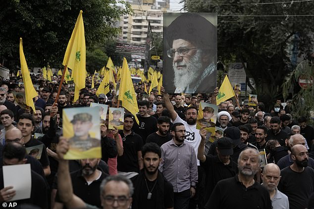 Supporters held up Hezbollah flags and photos of Akil (left) and Supreme Leader Ayatollah Ali Khamenei (right) during Akil's funeral procession.