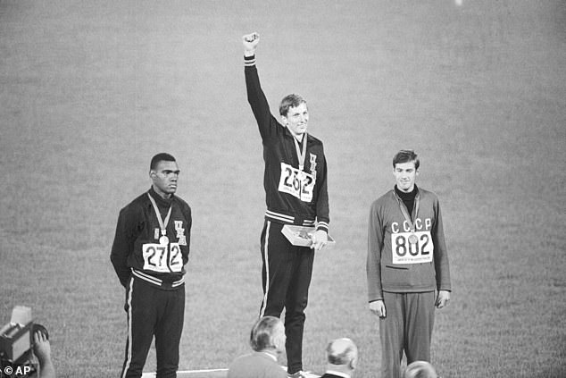 Gold medal winner Dick Fosbury raises his arm on the podium at the Olympic stadium in 1968.