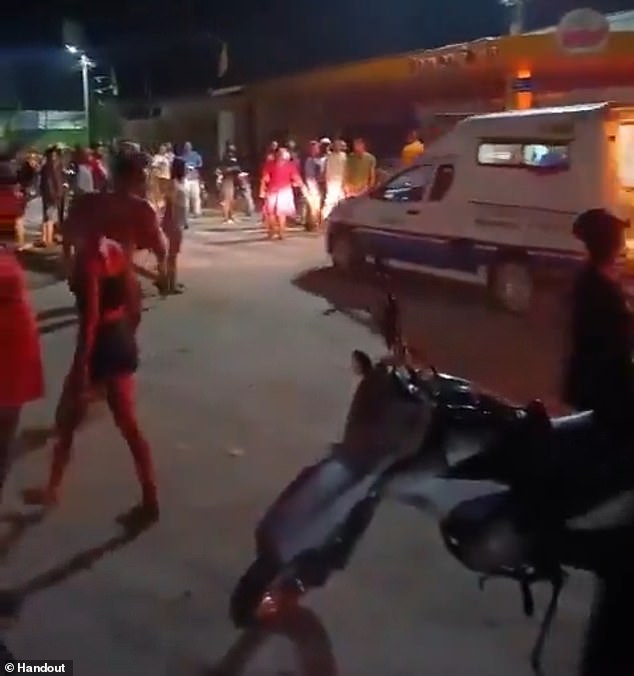 Residents surround an ambulance near the police station where an angry mob stormed on Thursday and removed Gregorio da Silva, who had allegedly confessed to the rape and murder of one-year-old Laylla de Assis, and set his body on fire.