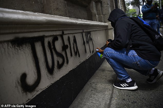 A student paints graffiti at the entrance of the Ministry of the Interior during a demonstration demanding justice for the 43 students from the Ayotzinapa Rural Teachers' College who disappeared on September 26, 2014.