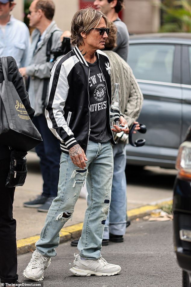 Keith looked relaxed in a black NYU T-shirt and distressed jeans, which he paired with a black and white bomber jacket.