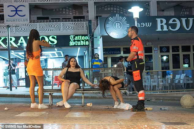 Paramedics attend to a girl who fainted on a bench on the tourist island of Mallorca