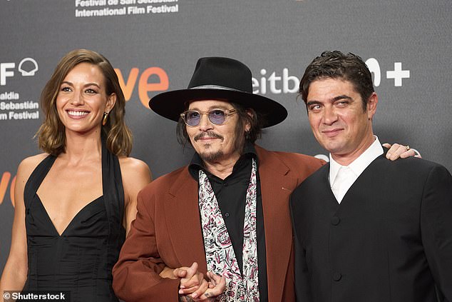 Depp walked the red carpet in a black shirt and a white scarf draped over his shoulders.