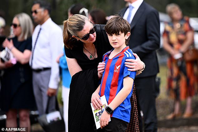 A woman is seen comforting a child at Ben and Russell Smith's funeral