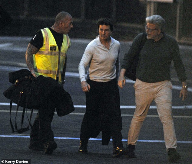 The Mission: Impossible star flew in by helicopter with a friend and was greeted by airport staff in a high-vis jacket.