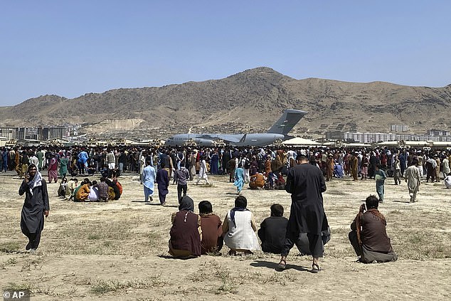 Hundreds of people gather near a U.S. Air Force C-17 transport plane on the perimeter of Kabul International Airport, Afghanistan, August 16, 2021.