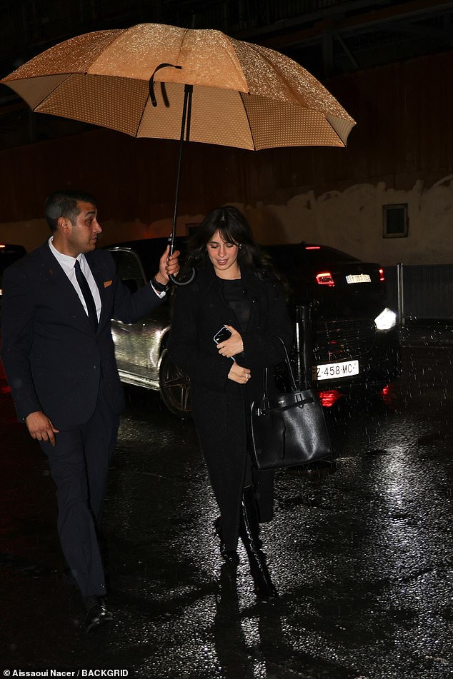 This time, Camila recruited a different umbrella handler as she entered the restaurant dressed all in black.