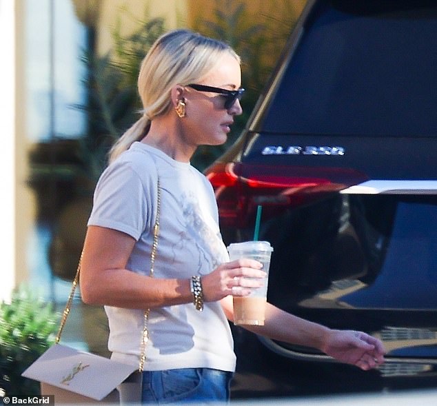 Stepping out of the 9,000-square-foot home, Jackie looked effortlessly chic in a relaxed ensemble as she walked with a drink in hand.