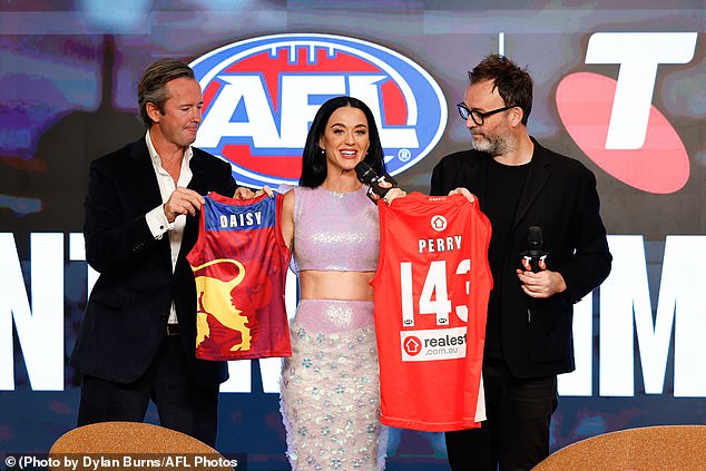 Perry tried her hand at Australian slang and AFL references at a press conference littered with 'speccy' and 'granny' after running around the turf in heels while practising handballs with AFLW stars.