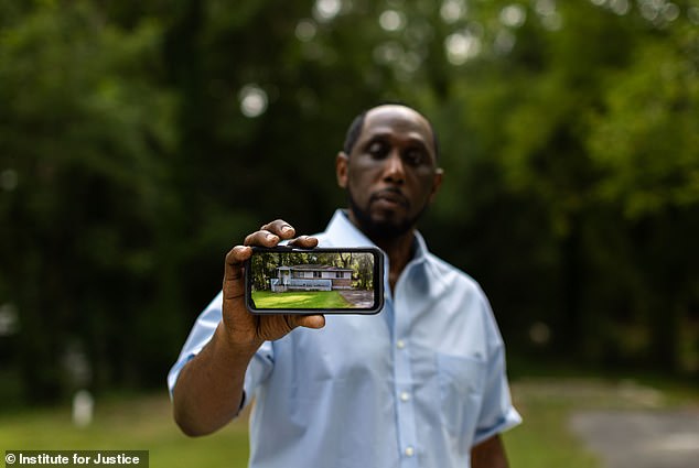 The devastated homeowner shows a photograph of what his property looked like before it was demolished.